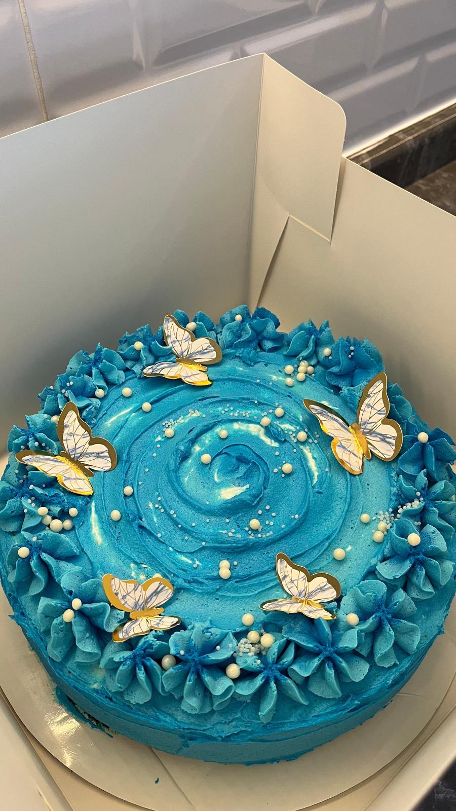 Mavi kremalı, beyaz kelebekler ve inci detaylarıyla süslenmiş pasta