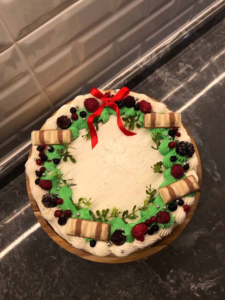 Orman meyveleri ve yeşil yapraklarla süslenmiş çelenk konseptli pasta